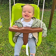 Lyam a rejoint le concours — aidez-le/la à gagner de superbes lots ! child, toddler, swing, green_swing, outdoor, grass, smiling, happy, jacket, leggings, shoes, playground, rope, nature, daylight, person, baby, park, fun, cute