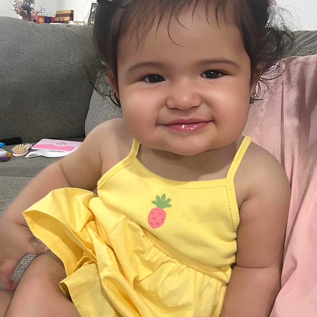 Audrina joined the competition — help win amazing prizes! baby, child, clothing, couch, curly_hair, cute, face, hair_bows, hand, happy, indoor, infant, person, pineapple_print, portrait, sitting, skin, smiling, toddler, yellow_dress