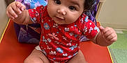 Skylar is registered to the contest to win money with this photo: baby, child, infant, red_onesie, pink_socks, curly_hair, orange_mat, backpack, indoor, floor_tiles, baby_gear, cute, chubby, sitting, reaching, portrait, young_child, playful, person, clothing