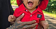 Ricardo Jasiel is registered to the contest to win money with this photo: baby, child, red_clothing, red_hat, laughing, tattooed_hand, adult, outdoor, trees, sunlight, park, greenery, smile, happy, person, casual_clothing, nature, daylight, sitting, holding