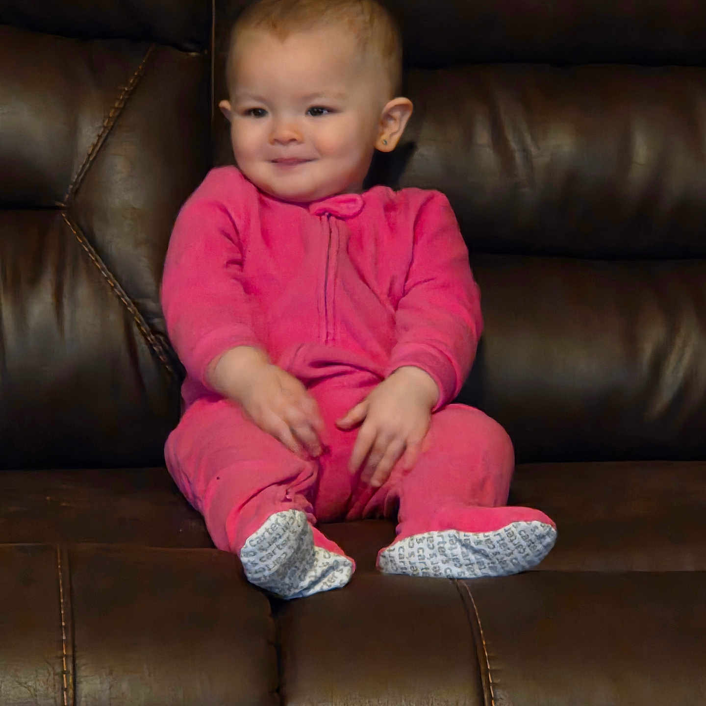 Isabela joined the competition — help win amazing prizes! baby, child, comfortable, cozy, cute, earrings, footwear, furniture, happy, home, indoor, infant, leather_couch, person, pink_onesie, portrait, relaxed, sitting, smile, young_child