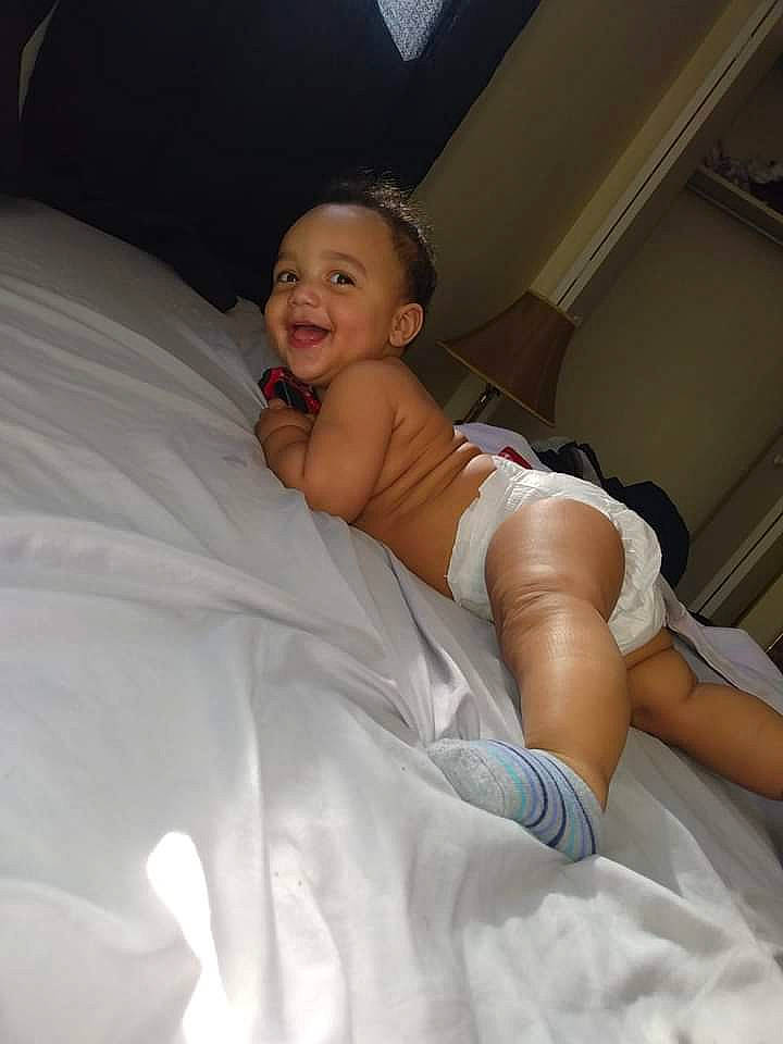 Uziah is registered to the contest to win money with this photo: abdomen, bed, bedding, bedroom, black_hair, chest, child, comfort, eye, eyebrow, finger, flash_photography, happy, joy, leg, linens, person, shoulder, skin, smile