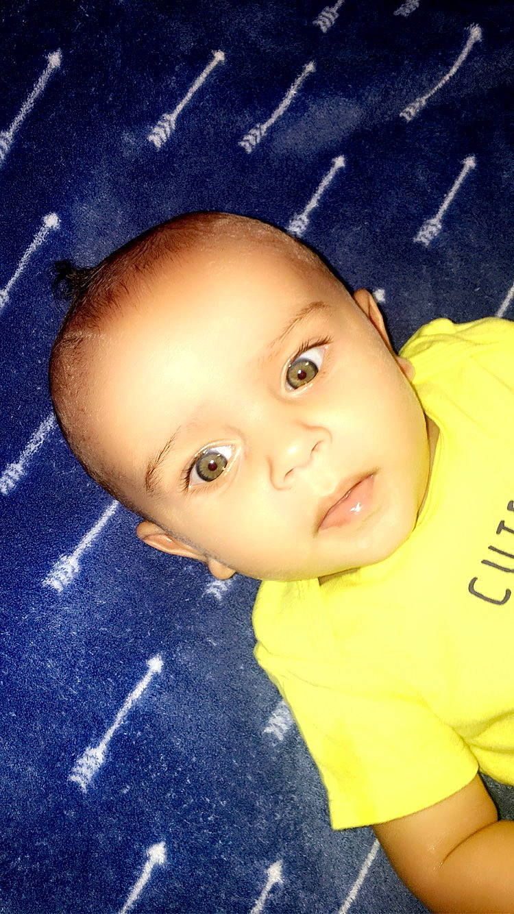 Hassan is registered to the contest to win money with this photo: baby, cheek, child, ear, eye, face, forehead, head, nose, person, skin, smile, toddler, yellow