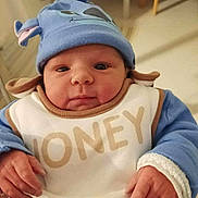 Maylan a rejoint le concours — aidez-le/la à gagner de superbes lots ! baby, infant, blue_hat, bib, clothing, hands, face, indoor, person, cute, newborn, chubby_cheeks, seated, soft_lighting, background_blur, warm_clothes, expression, human, child, holding
