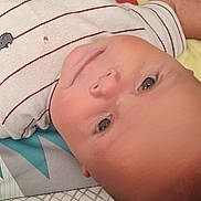 Johnnie is registered to the contest to win money with this photo: baby, blanket, child, clothing, cute, expression, eyes, face, floor, head, indoor, infant, lying_down, patterned_blanket, portrait, relaxed, skin, soft_light, striped_shirt, young_child