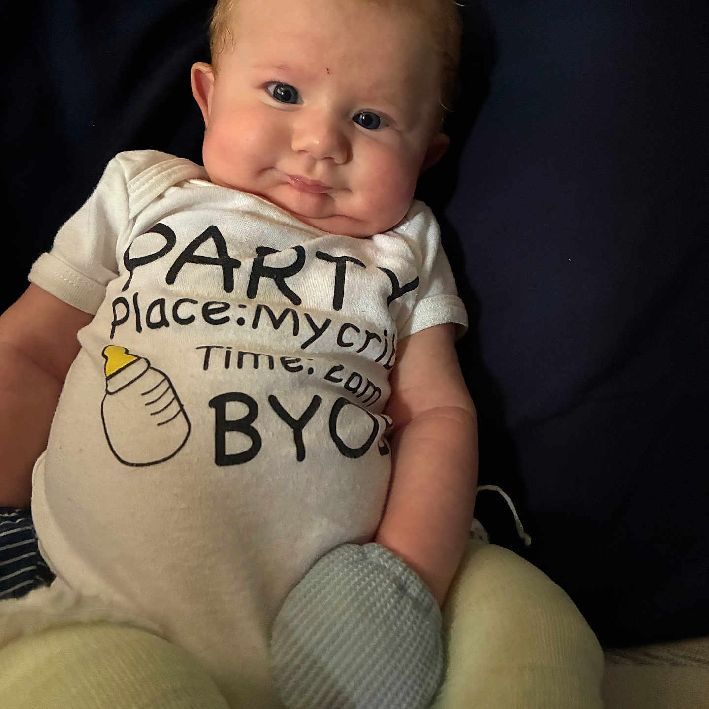 Waylon is registered to the contest to win money with this photo: baby, infant, onesie, clothing, pillow, mittens, cute, face, chubby_cheeks, expression, lying_down, indoor, person, child, portrait, cozy, soft_lighting, funny_text, bottle_illustration, comfortable