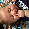 baby, blanket, close_up, clothing, colorful, curly_hair, cute, face, fingers, fist, hands, indoors, infant, lying_down, pajamas, patterned, portrait, relaxed, sleeping, stars