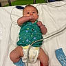 baby, infant, hospital, medical, bed, diaper, sock, cuff, cable, green_shirt, blue_sock, red_cuff, lying_down, person, healthcare, newborn, cute, indoors, medicine, patient