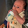 Waylon joined the competition — help win amazing prizes! baby, bottle, feeding, onesie, infant, cute, tiger, hand, couch, adult, comfort, milk, clothing, face, portrait, child, indoor, person, resting, cozy