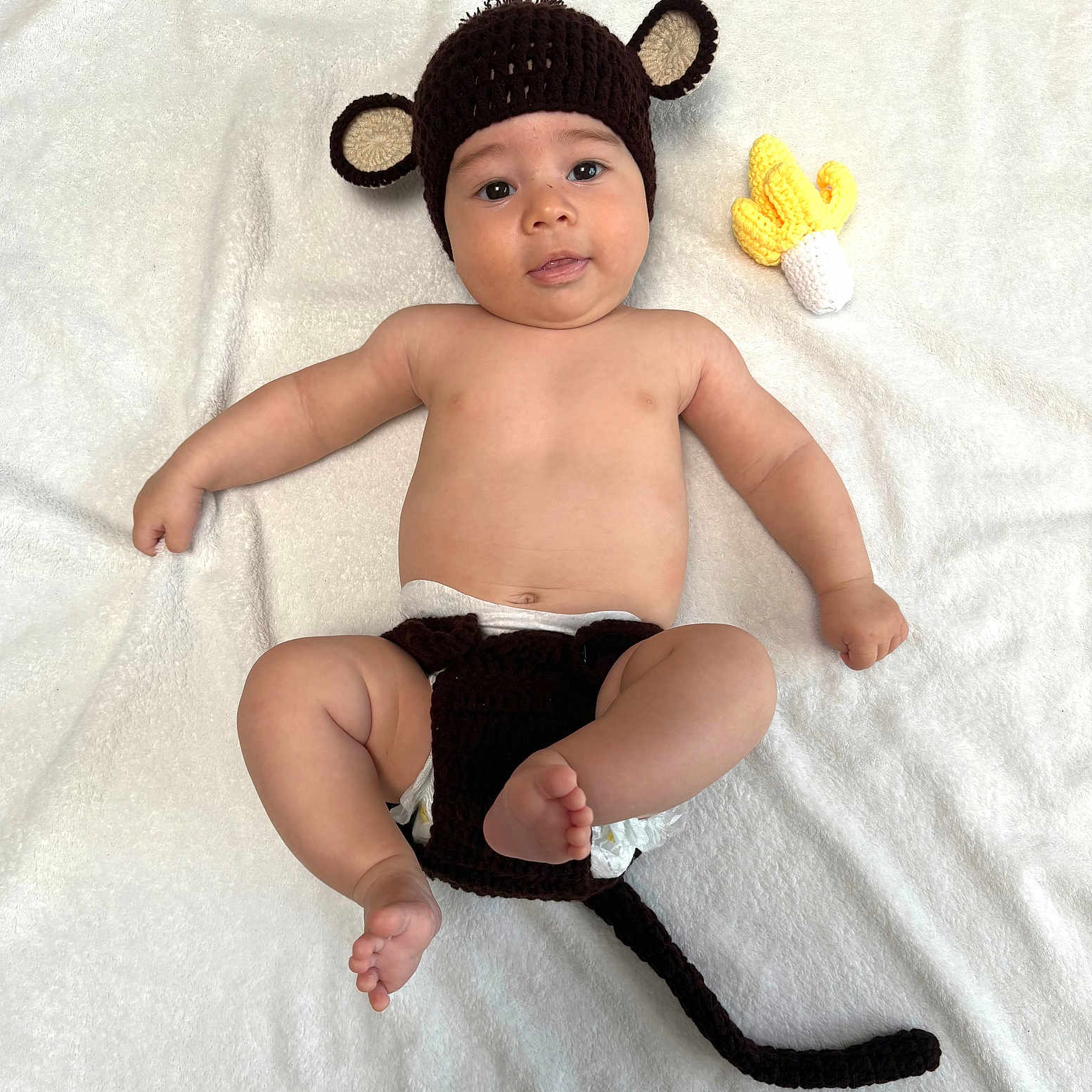 Yzac participe au concours pour gagner de l'argent avec cette photo : adorable, baby, banana, bare_chest, child, chubby_cheeks, crocheted, cute, diaper, headwear, indoors, infant, infant_clothing, lying_down, monkey_hat, playful, smiling, soft_blanket, toddler, toy