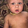 Anthony Jr. is registered to the contest to win money with this photo: baby, child, face, eyes, necklace, beads, skin, expression, mouth, arm, cushion, pattern, indoor, portrait, curious, young, infant, closeup, person, sitting