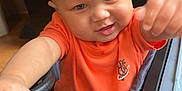 Anthony Jr. joined the competition — help win amazing prizes! baby, child, orange_shirt, toy_car, steering_wheel, indoor, playtime, cute, face, head, hands, expression, young_child, infant, person, vehicle, fun, smile, play, seat