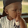 toddler, child, baseball, cap, jersey, striped_clothing, thumb_sucking, portrait, outdoor, soft_focus, cute, baby, hat, sports, young_child, casual_clothing, hand, face, expression, daylight