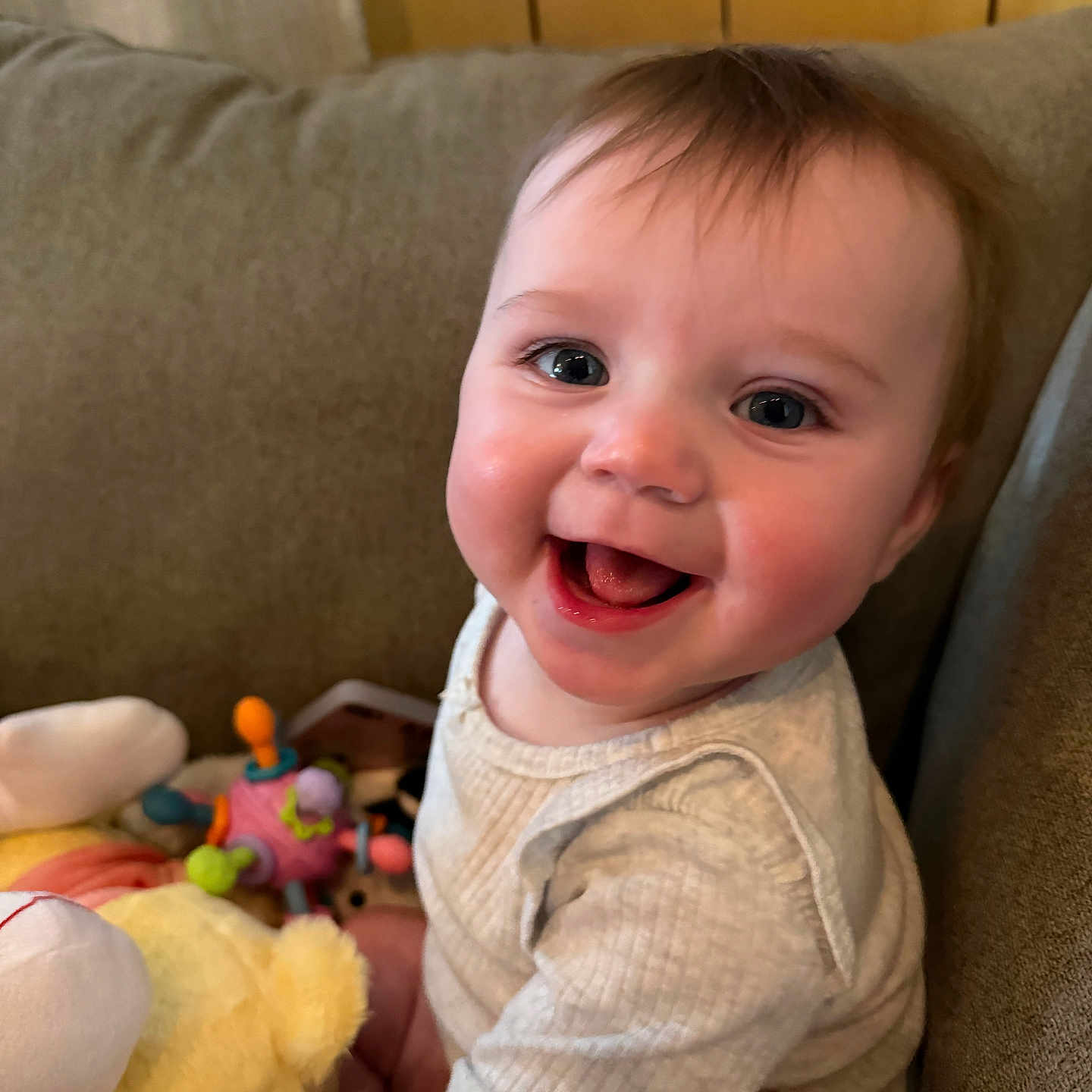 Skyler joined the competition — help win amazing prizes! baby, child, smile, happy, cute, face, indoors, toy, plush_toy, couch, clothing, person, infant, sitting, bright_eyes, cheerful, home, young_child, playtime, cozy