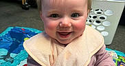 Skyler is registered to the contest to win money with this photo: baby, baby_seat, bib, child, crib, cute, face, hair, hands, happy, indoor, infant, person, pink_clothing, playmat, rosy_cheeks, seated, smiling, toddler, toy