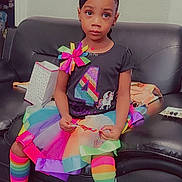 Lyric is registered to the contest to win money with this photo: child, clothing, couch, doll, face, female, footwear, furniture, girl, head, hosiery, person, photography, portrait, purple, shoe, sitting, sleeve, sock, toy