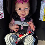 Sutton is registered to the contest to win money with this photo: baby, beads, blue_eyes, car_seat, child, close_up, clothing, cute, fingers, hand, happy, infant, leggings, pacifier, pink_bow, portrait, safety_harness, seatbelt, smiling, sunlight