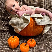 Sutton is registered to the contest to win money with this photo: baby, pumpkin, blanket, infant, orange, decorative, cute, child, fall, autumn, cozy, knit, fabric, pattern, small_pumpkins, wrapped, portrait, indoor, smiling, face