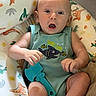Cohen is registered to the contest to win money with this photo: baby, infant, child, onesie, toy, comb, dinosaur_print, baby_seat, colorful, surprised_expression, cute, indoor, soft_lighting, skin, face, hands, legs, blue, green, play