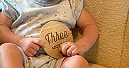 Cohen joined the competition — help win amazing prizes! baby, beige_chair, blue_clothing, child, comfortable, cozy, curious, cute, expression, face, feet, hands, indoor, infant, person, plaque, portrait, sitting, wooden, young_child