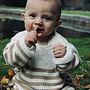 Tyliano a rejoint le concours — aidez-le/la à gagner de superbes lots ! baby, child, grass, leaf, sweater, striped, brown_pants, outdoor, nature, fall, autumn, curious, sitting, young_child, portrait, hands, face, eyes, nose, cozy