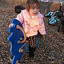toddler, child, playground, spring_rocker, blue_horse, pink_jacket, black_boots, wood_chips, bicycle, backpack, concrete_ledge, outdoor, daylight, casual_clothing, young_child, play_equipment, park, person, nature, fun