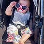 baby, stroller, sunglasses, heart_shaped, pacifier, child, outdoor, sunlight, summer, clothing, floral, foot, hand, seatbelt, black, white, pink, cute, relaxed, portrait