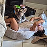 child, toddler, baby, french_bulldog, dog, pet, indoor, sitting, lying_down, bottle, toy, pet_bed, animal, portrait, home, tile_floor, colorful_bowls, casual, playful, funny