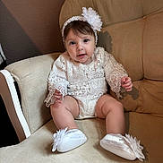 Mckenna is registered to the contest to win money with this photo: baby, infant, child, lace, headband, flower, white_clothing, shoes, cushion, chair, indoor, portrait, cute, sitting, soft_lighting, smile, happy, furniture, person, closeup