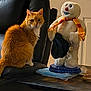 cat, orange_cat, tabby, plush_toy, snowman, scarf, hat, chair, leather_chair, table, papers, indoor, pet, furniture, cozy, home, animal, sitting, cute, domestic