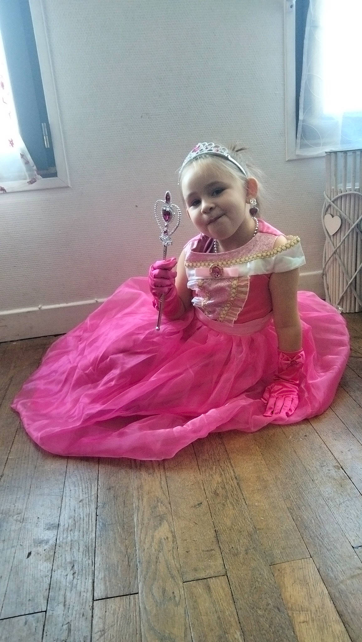 Elya a rejoint le concours — aidez-le/la à gagner de superbes lots ! baby_toddler_clothing, child, costume, dress, embellishment, event, floor, flooring, fun, happy, hardwood, joy, magenta, person, pink, purple, room, sitting, smile, toddler