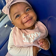 Taishaly joined the competition — help win amazing prizes! baby, child, smile, face, headband, bow, clothing, bib, pink, happy, seat, blue, person, infant, cute, portrait, hands, eyes, apparel, sitting
