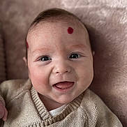 Loan participe au concours pour gagner de l'argent avec cette photo : baby, baby_clothing, cheeks, close_up, cute, eyes, face, happy, head, indoor, infant, knitted_sweater, mouth, portrait, red_dot, skin, smiling, soft_blanket, sweater, tongue