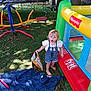 child, toddler, grass, playground, inflatable, snack_bag, barefoot, towel, outdoor, toy, play_structure, tree, fence, summer, sunlight, clothing, face, messy, person, nature