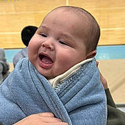 Josue is registered to the contest to win money with this photo: baby, child, infant, smiling, blanket, holding, hand, face, cheeks, wrapped, blue, clothing, indoors, person, happy, portrait, head, young, cute, warm