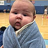 Josue joined the competition — help win amazing prizes! baby, child, face, blanket, blue_blanket, indoor, gymnasium, sports, curious, wrapped, cozy, person, portrait, young_child, cute, chubby_cheeks, human, expression, warm, soft