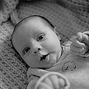 Maël a rejoint le concours — aidez-le/la à gagner de superbes lots ! baby, infant, black_and_white, knitted_blanket, close_up, face, hand, cute, child, young, portrait, expression, soft, texture, warm, cozy, newborn, person, sleepwear, lying_down