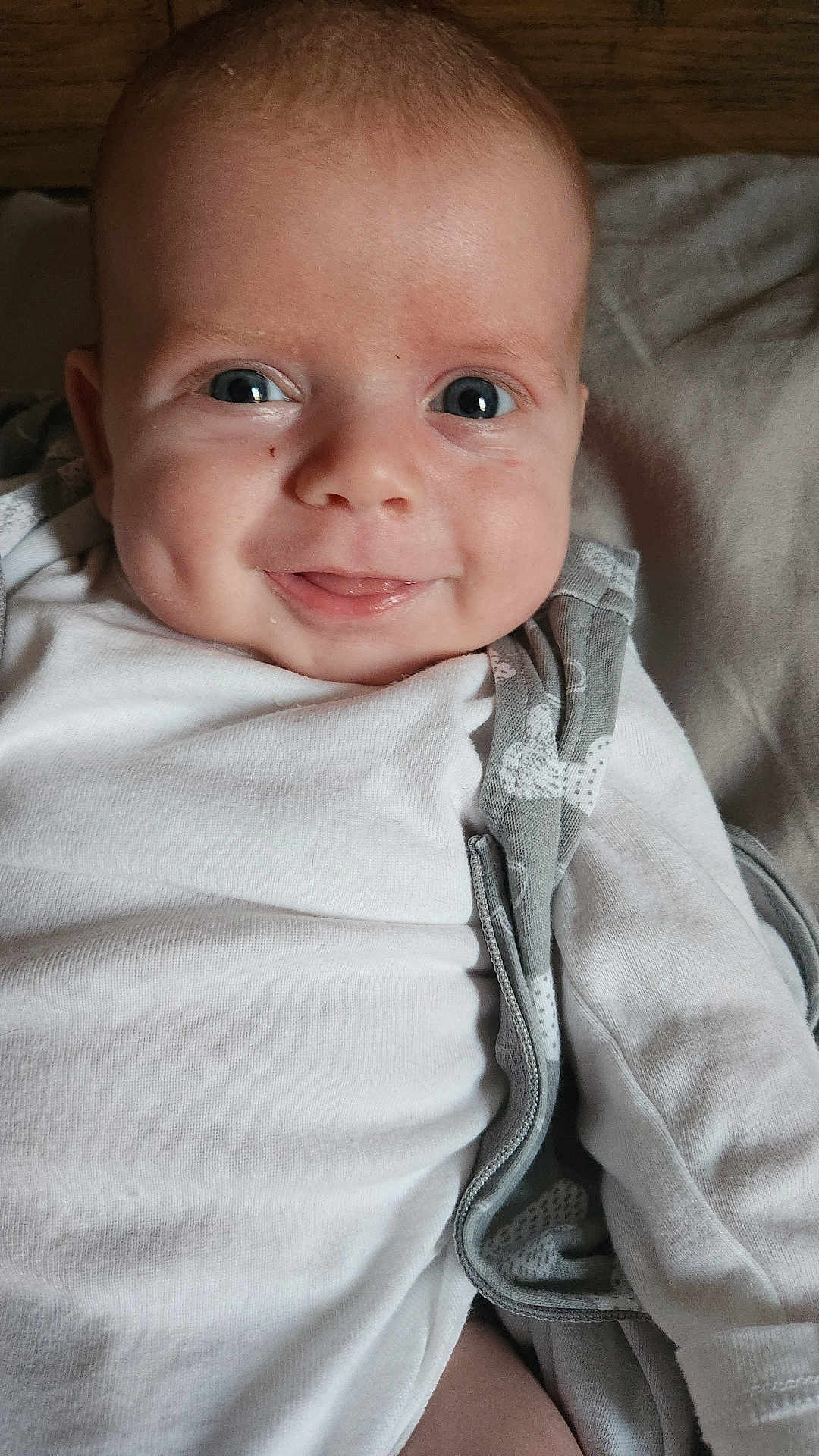 Kayden is registered to the contest to win money with this photo: baby, infant, smiling, face, eyes, dimples, white_clothing, blanket, soft_surface, closeup, cute, child, young, portrait, indoors, happy, lying_down, skin, head, expression