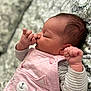 newborn, baby, sleeping, pink_clothing, cute, thumb_sucking, infant, striped_sleeves, peaceful, closeup, face, hand, blanket, patterned_background, soft_light, portrait, child, resting, cozy, cute_outfit