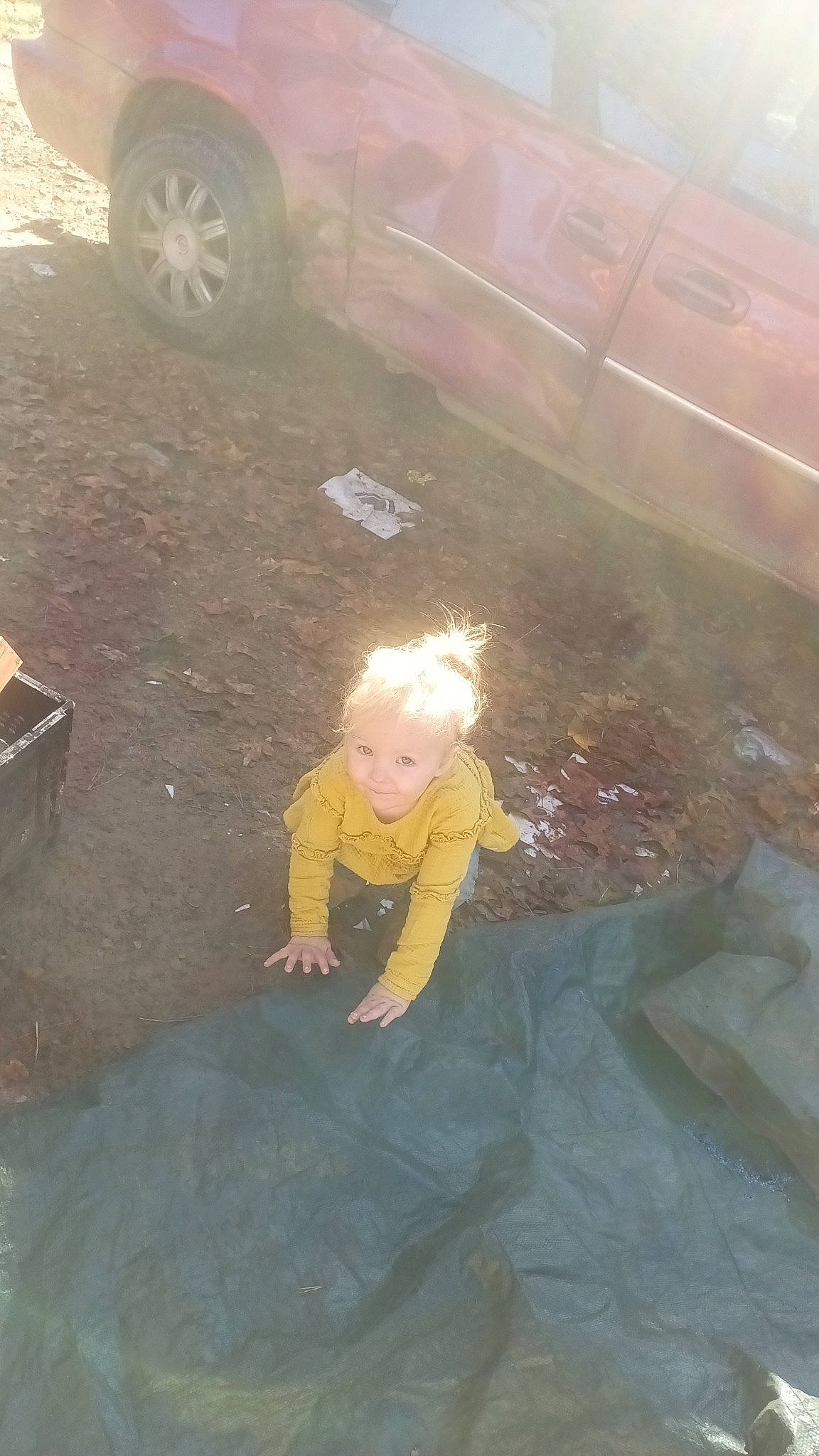 Evelyn is registered to the contest to win money with this photo: asphalt, automotive_tire, baby, car, child, concrete, family_car, floor, flooring, fun, grass, joy, person, recreation, road_surface, shadow, sitting, soil, tints_and_shades, tire