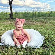 Emery joined the competition — help win amazing prizes! baby, child, infant, smiling, outdoor, field, grass, countryside, nature, pink_bow, romper, cushion, sitting, portrait, sunlight, clouds, fence, tree, pasture, happy