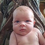 Nolan joined the competition — help win amazing prizes! baby, infant, bare_chest, person, face, eyes, skin, head, legs, camouflage, clothing, indoor, furniture, sitting, closeup, expression, newborn, child, human, portrait