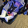 baby, infant, sleeping, stroller, car_seat, furry_hood, blanket, warm_clothing, white_pants, socks, teething_rings, toy, carpet, indoors, portrait, peaceful, cozy, harness, straps, close_up