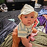 adult_hand, adult_leg, baby, bed, bedroom, blanket, child, clothing, dog, dresser, home, indoor, infant, laundry, photography, portrait, sitting, striped_shirt, sun_hat, wide_eyes