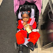 Aëla participe au concours pour gagner de l'argent avec cette photo : black_shoes, carpet, casual, child, concentration, cute, drinking, floor_tiles, indoor, person, pink_canopy, puffy_hair, red_clothing, seat_belt, shopping_area, small_purse, snack_time, stroller, sunglasses, toddler