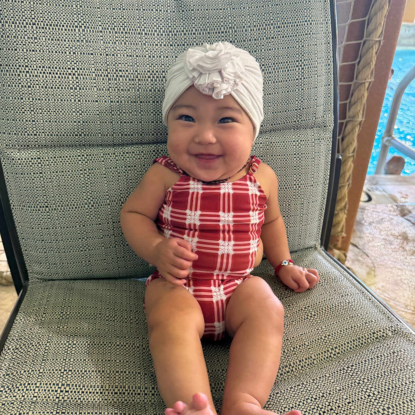 Kissaevynn is registered to the contest to win money with this photo: baby, barefoot, bracelet, chair, child, cute, flower, happy, headwear, indoors, infant, patterned_chair, plush, poolside, portrait, sitting, skin, smiling, swimsuit, turban