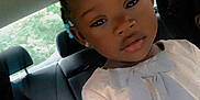 Anari is registered to the contest to win money with this photo: african_american, bow, calm, car_interior, casual, child, curious, daylight, dress, girl, hair_ties, hairstyle, indoors, person, portrait, seat, seated, vehicle, window, young