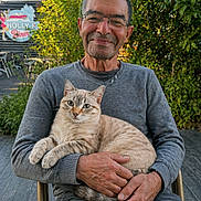 ķazanouva participe au concours pour gagner de l'argent avec cette photo : animal, casual_clothing, cat, chair, cream_colored_cat, daylight, glasses, greenery, grey_sweater, hands, happy, man, nature, older_adult, outdoor, pet, portrait, relaxed, sitting, smiling