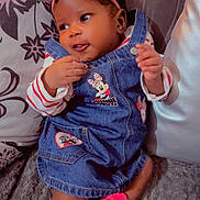 Mayra participe au concours pour gagner de l'argent avec cette photo : baby, child, infant, denim_dress, pink_bow, headband, socks, couch, pillow, cozy, cute, smiling, indoors, soft_texture, clothing, person, portrait, small_baby, playful, relaxed
