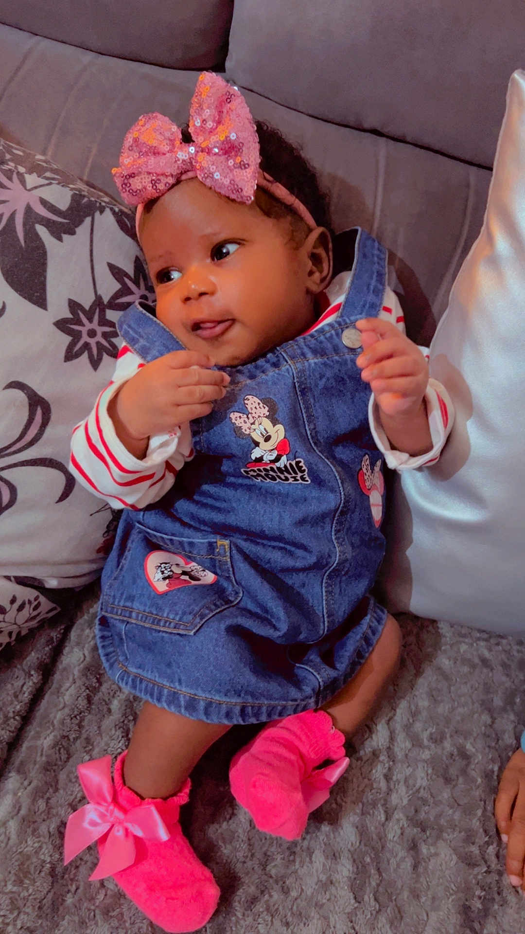Mayra participe au concours pour gagner de l'argent avec cette photo : baby, child, infant, denim_dress, pink_bow, headband, socks, couch, pillow, cozy, cute, smiling, indoors, soft_texture, clothing, person, portrait, small_baby, playful, relaxed
